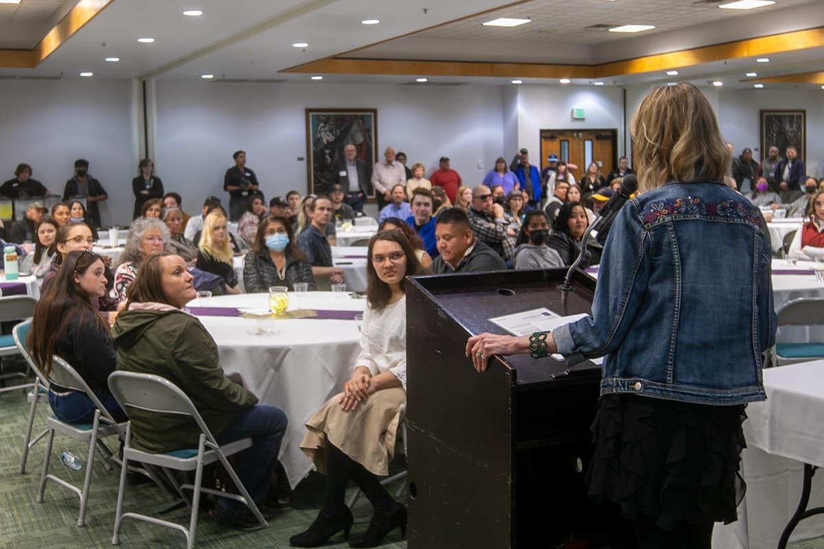 Person standing at podium speaking to a crowd of people.